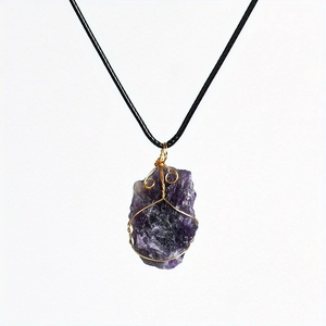 Detail of natural purple amethyst raw stone necklace with gold wire wrap and black cord