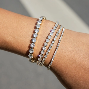 Dettaglio di quattro bracciali tennis dorati con diverse dimensioni di pietre sul polso