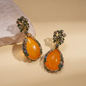 Détail des boucles d'oreilles poires en résine ambre vintage avec des accents de fleurs en strass