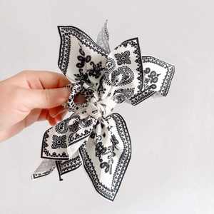 Close-up of a large black and white paisley bow hair claw clip held in hand