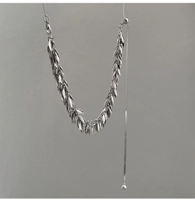 Close-up of silver-tone sequin fringe necklace with polished metallic leaf tassels