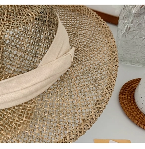 Detail of handwoven seagrass hat featuring fine texture and cream cotton ribbon bow