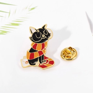 Detail of cute enamel cat pin wearing a striped scarf and riding a magical broomstick