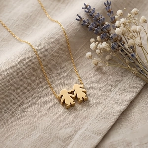 Detailed shot of golden boy and girl silhouette pendant on a textured fabric surface