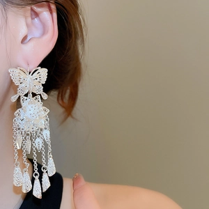 Detailed view of silver butterfly flower tassel earrings worn on a model's ear