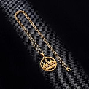 Detailed macro view of the gold-tone Lalish pendant necklace on dark textured background