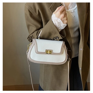 Détail du sac à main en cuir litchi blanc avec bordure taupe et fermoir pivotant doré