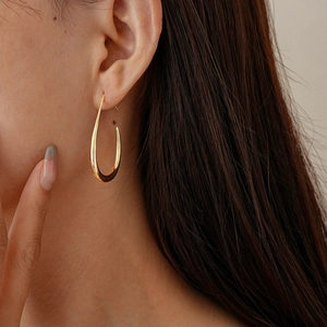 Close-up of elegant gold drop earrings on a model showing the polished metallic finish