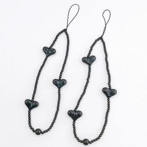 Detail of two black beaded phone wrist straps with smooth heart-shaped acrylic charms