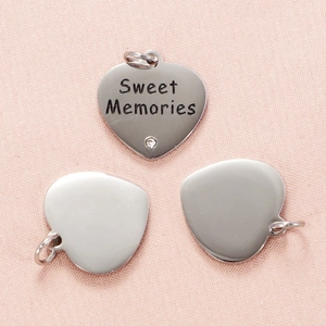 Vue macro de pendentifs cœur en acier inoxydable avec gravure Sweet Memories et petit cristal