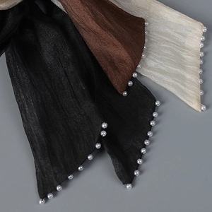 Detailed close-up of pleated sun hat ribbons with elegant pearl edges in three colors