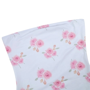 Close-up detail of pink rose floral print on soft white fabric of the strapless dress