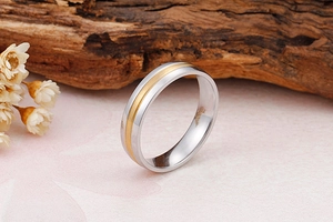 Détail d'une bague bicolore en acier inoxydable avec rayure dorée sur socle en pierre