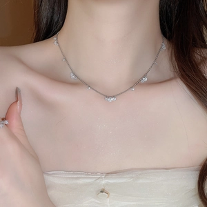 Close-up of silver necklace with zircon pendants and matching ring worn by a model