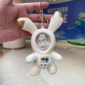 Detail of white astronaut rabbit plush keychain with golden ears and color foam balls