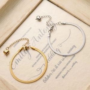 Detail of gold and silver blade chain bracelets with heart charms on elegant background