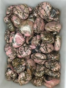 Close-up of polished heart-shaped pink rhodonite stones with unique black veins