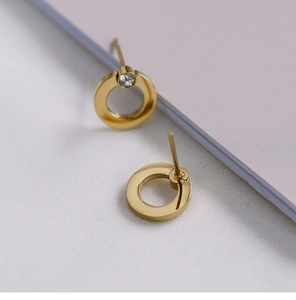 Close-up of gold geometric circle stud earrings with a single diamond inlay detail