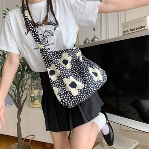 Navy canvas shoulder bag with white floral pattern worn in a cozy home setting