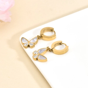 Gold butterfly earrings with white mother of pearl and diamonds against pink flowers