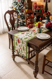 Close-up of woven Christmas table runner with festive tree patterns and green tassels