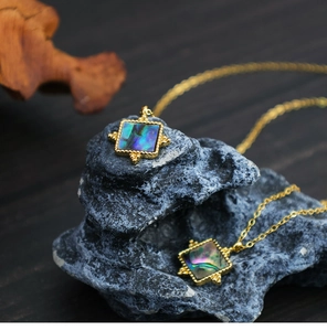 Macro view of square abalone shell pendant necklace in vintage gold bezel setting