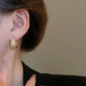 Close-up of golden U-shaped hoop earrings with pave-set cubic zirconia on female model