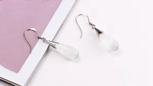 Macro shot of elegant teardrop cat eye stone earrings with polished silver hooks