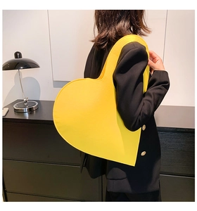 Close-up of bright yellow heart-shaped felt handbag with premium stitching details