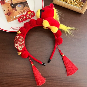 Detail of red Chinese New Year headband with plush pony, tassels and lucky charms