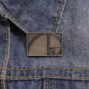 Vintage bronze Fibonacci spiral rectangle metal brooch on blue denim fabric