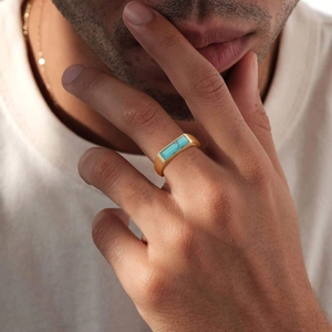Men's gold-plated stainless steel ring with rectangular turquoise stone worn on finger