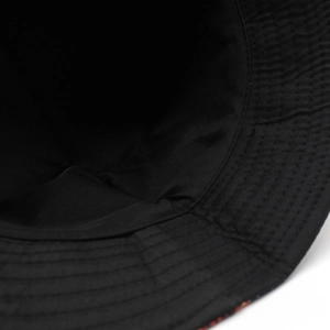 Détail macro montrant les coutures renforcées du bord et la doublure d'un chapeau bob noir