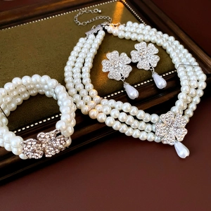 Detail of silver multi-layer pearl necklace and earrings with rhinestone clover charms