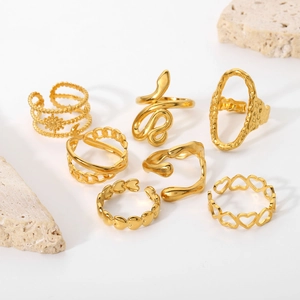 Flat lay of a 7-piece set of 18K gold-plated rings with snake and heart designs on stone
