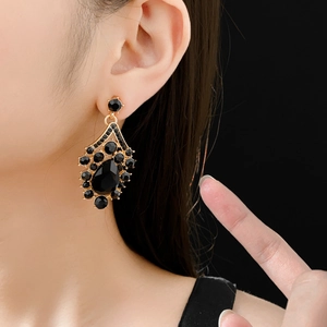 Close-up of vintage gold drop earrings featuring black rhinestones on a female model