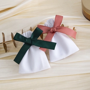 White velvet drawstring pouches with dark green and pink ribbon bows for jewelry gifts