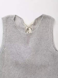 Détail du gilet en maille grise avec un ruban en satin blanc noué à l'arrière du col