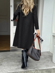 Women's minimalist long black trench coat paired with stylish knee-high boots