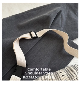 Detail of adjustable beige woven strap and black plastic buckle on a grey twill chest bag