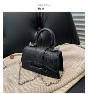 Detail of black pebbled leather mini handbag with curved flap and silver beaded chain strap