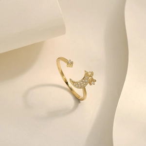 Detail of adjustable gold ring featuring a pavé zircon moon and hanging star charms