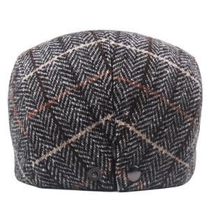Macro detail of men's tweed newsboy hat showing herringbone pattern and metal buckle