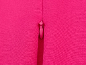 Detailaufnahme des verdeckten Reißverschlusses am eleganten bauchfreien Anzug in Rosarot