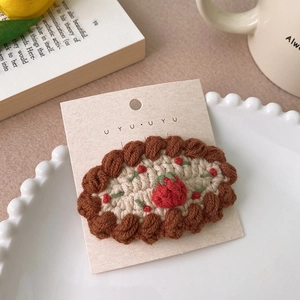 Vue détaillée d'une pince à cheveux tricotée main avec motif de fraise sur carte cadeau