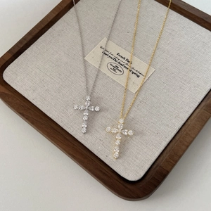 Macro detail of gold and silver S925 sterling silver cross necklaces on a wooden tray
