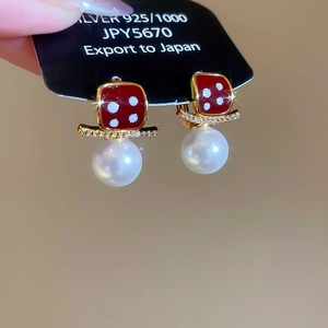 Macro shot of 18K gold plated earring with red enamel, zircons, and white pearl drop