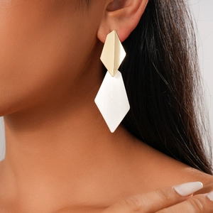 Close-up of geometric diamond earrings in gold and silver finish worn by a model