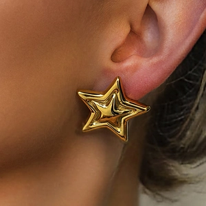 Minimalist gold star earrings with glossy metallic finish shown on model's earlobe