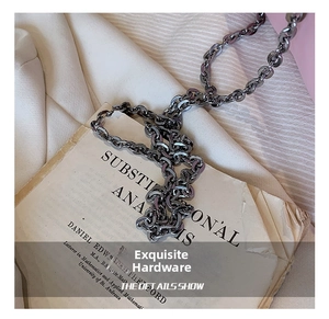 Close-up of thick dark grey metal chain strap on vintage book for cloud bag